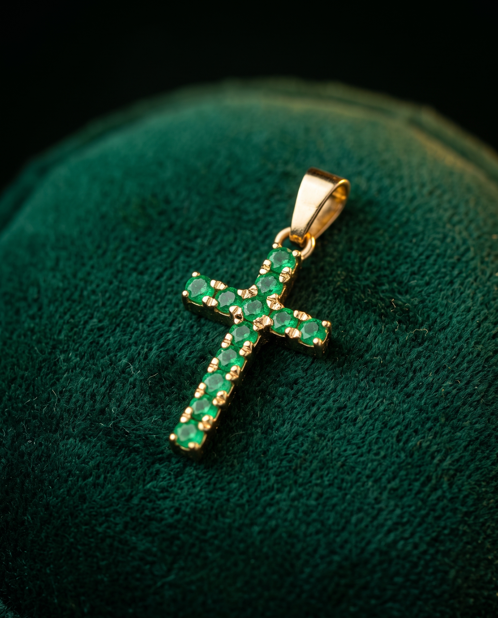 Dije cruz de esmeraldas sobre terciopelo verde, a su tamaño real